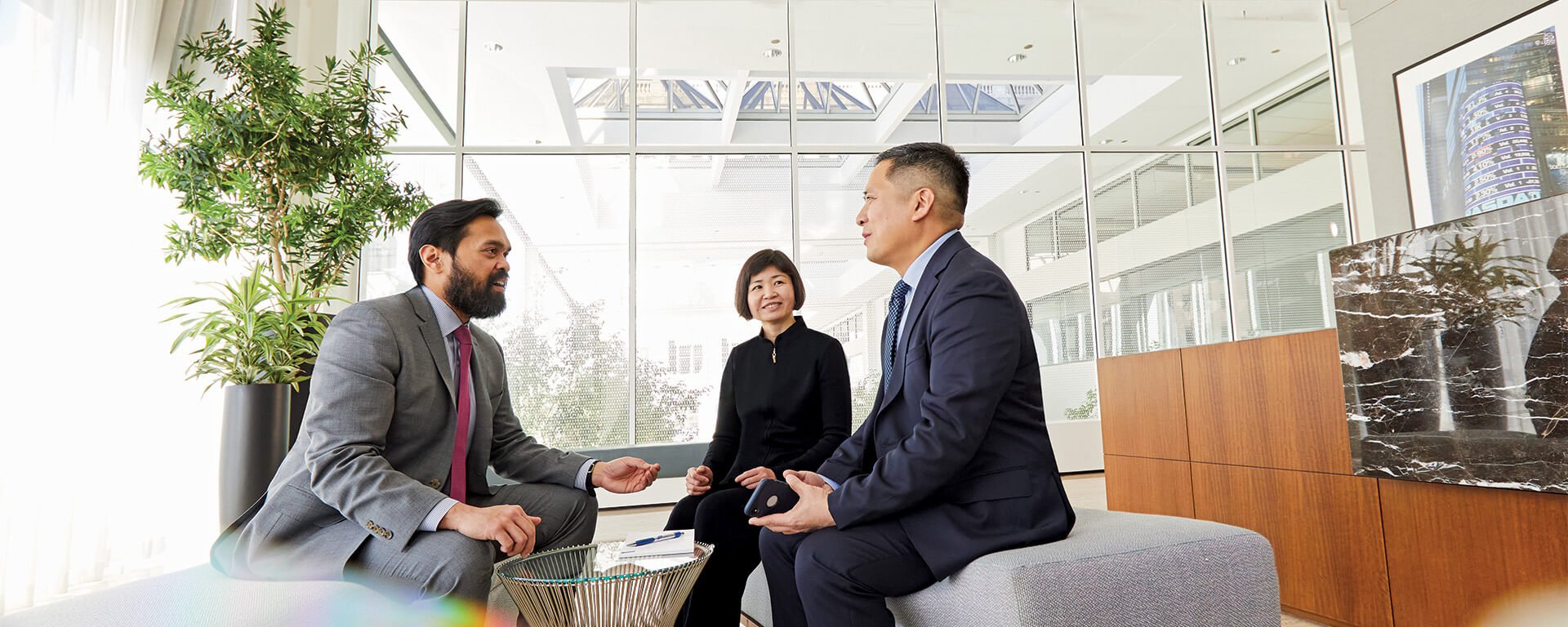 Three associates from the Chautauqua team engaged in conversation in an open office area